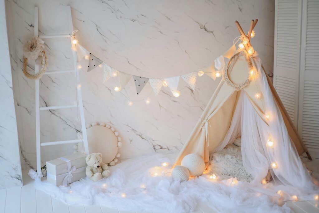A cozy children's play area with a decorative tent, string lights, and a plush teddy bear.
